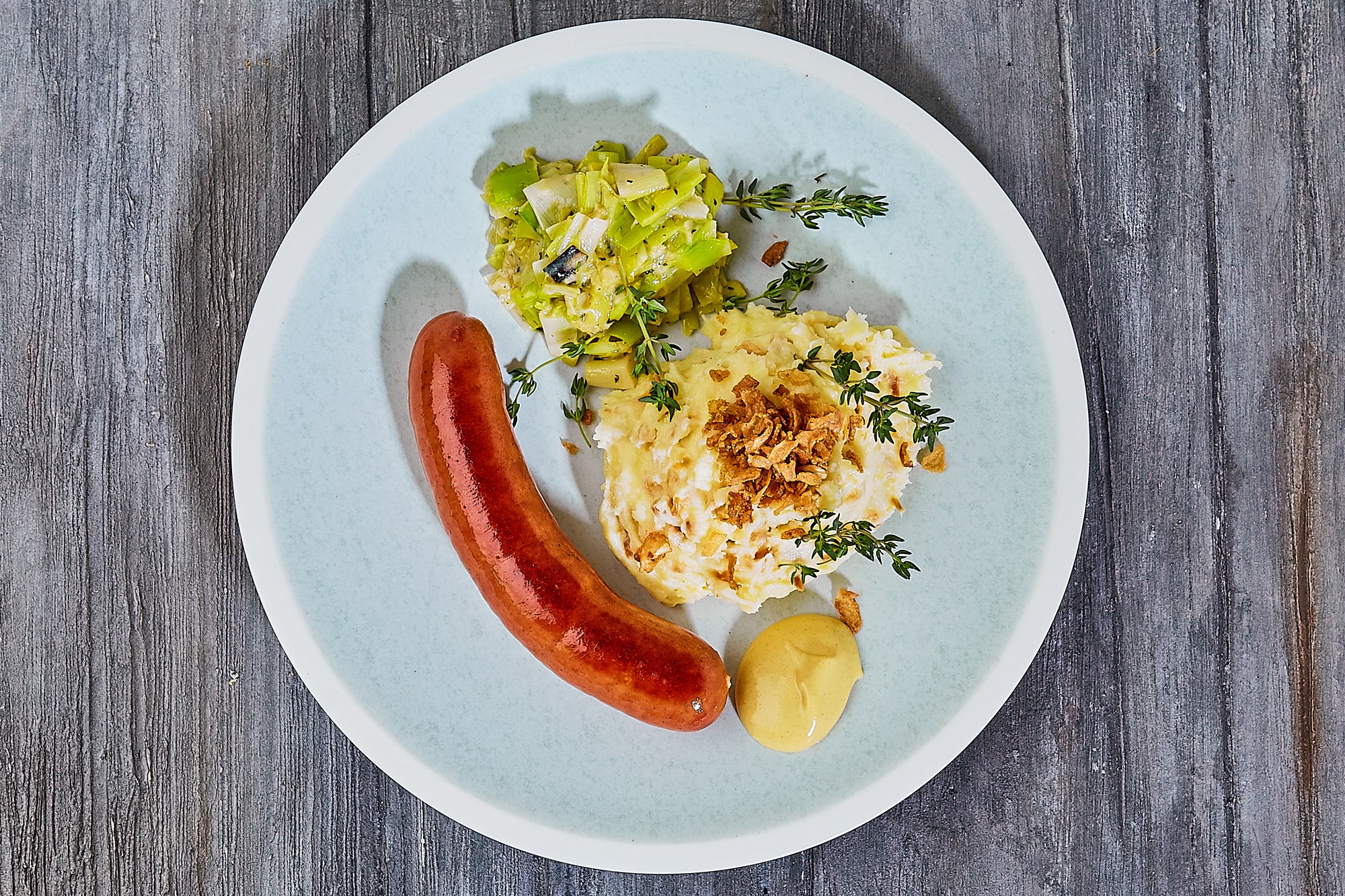Frankfurter med kartoffelmos rørt med ristede løg dertil timianstuvede porrer