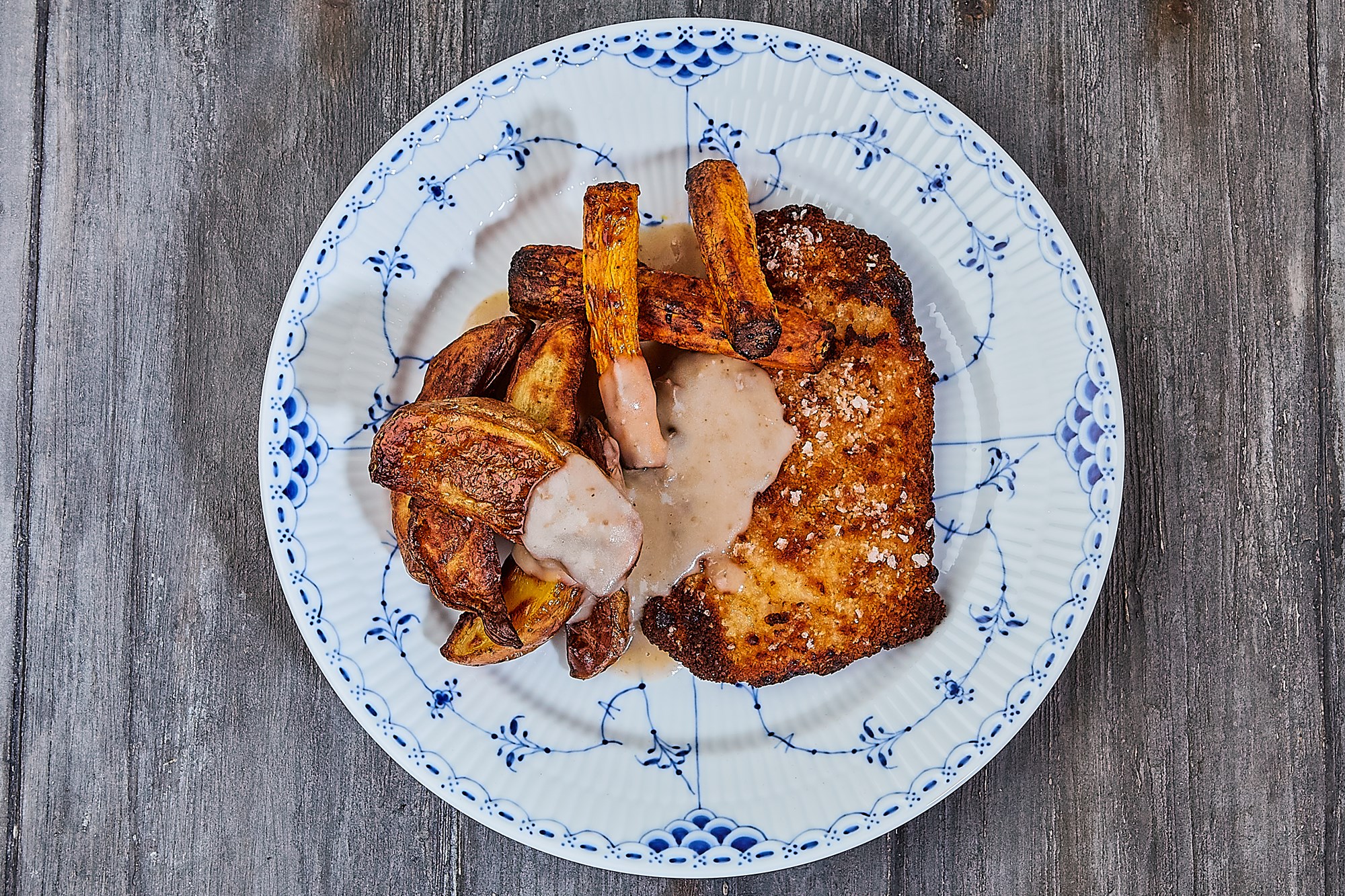 Skinkeschnitzel med stegte kartofler og gulerødder samt svampesovs