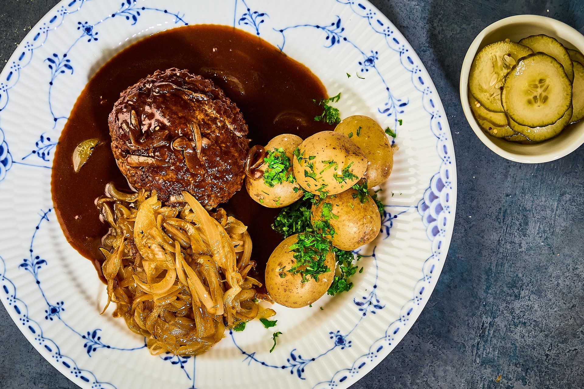 Dansk bøf med bløde løg, pandesovs, agurkesalat & hvide kartofler ...