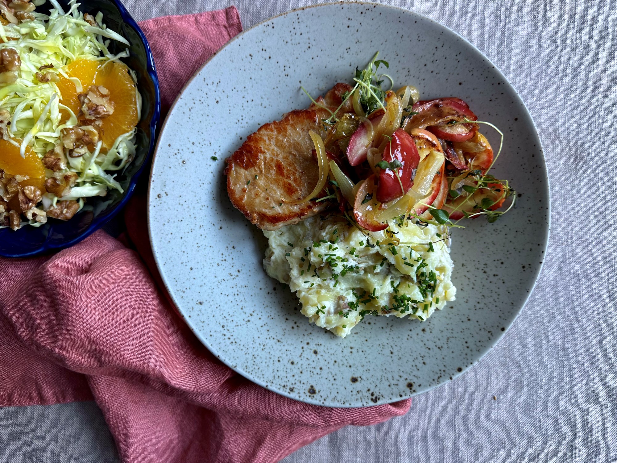 Koteletter med stegte løg og æbler, kålsalat og knuste, cremede kartofler