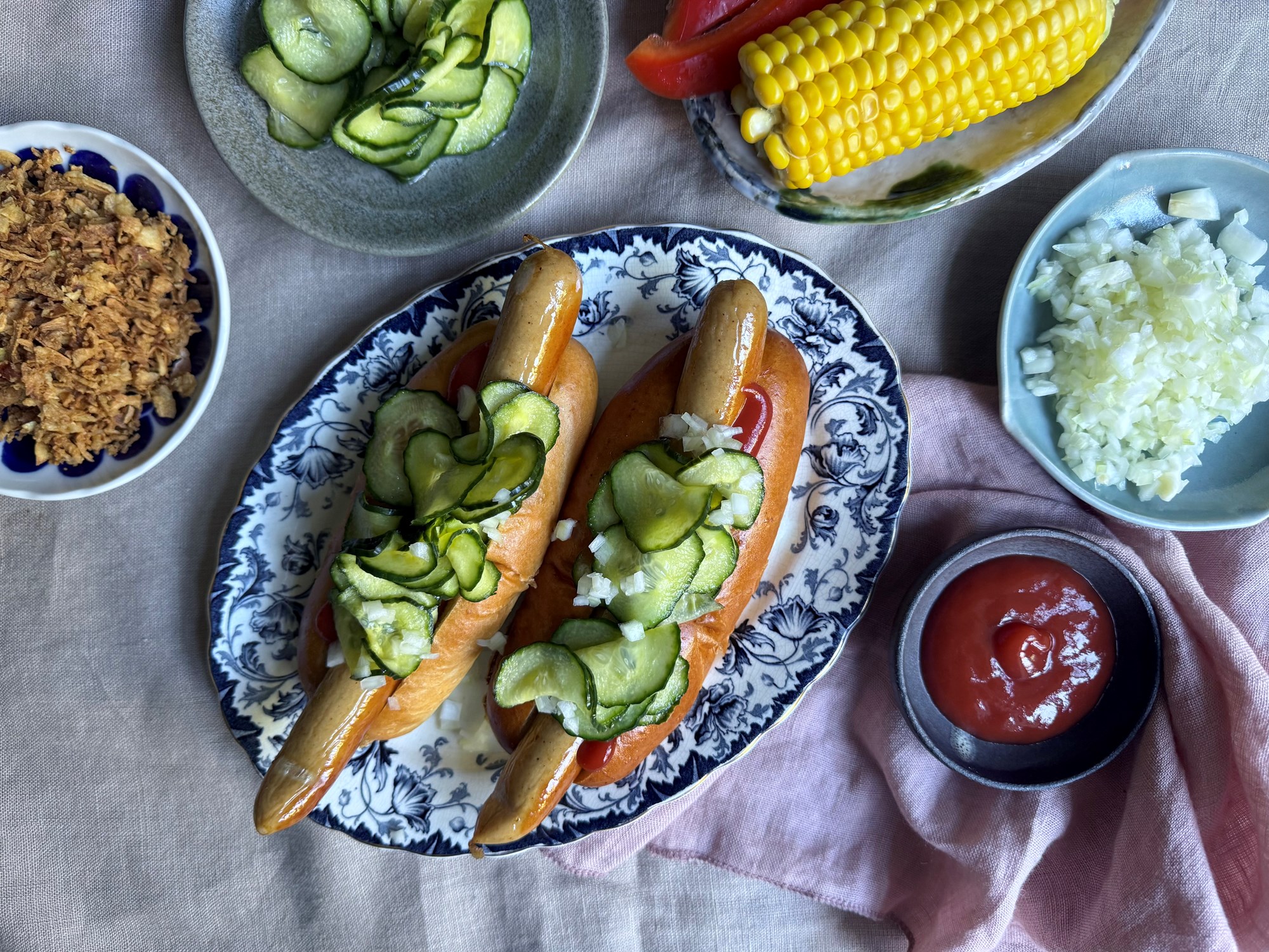 Hotdogs med agurkesalat, ristede løg og lune majs