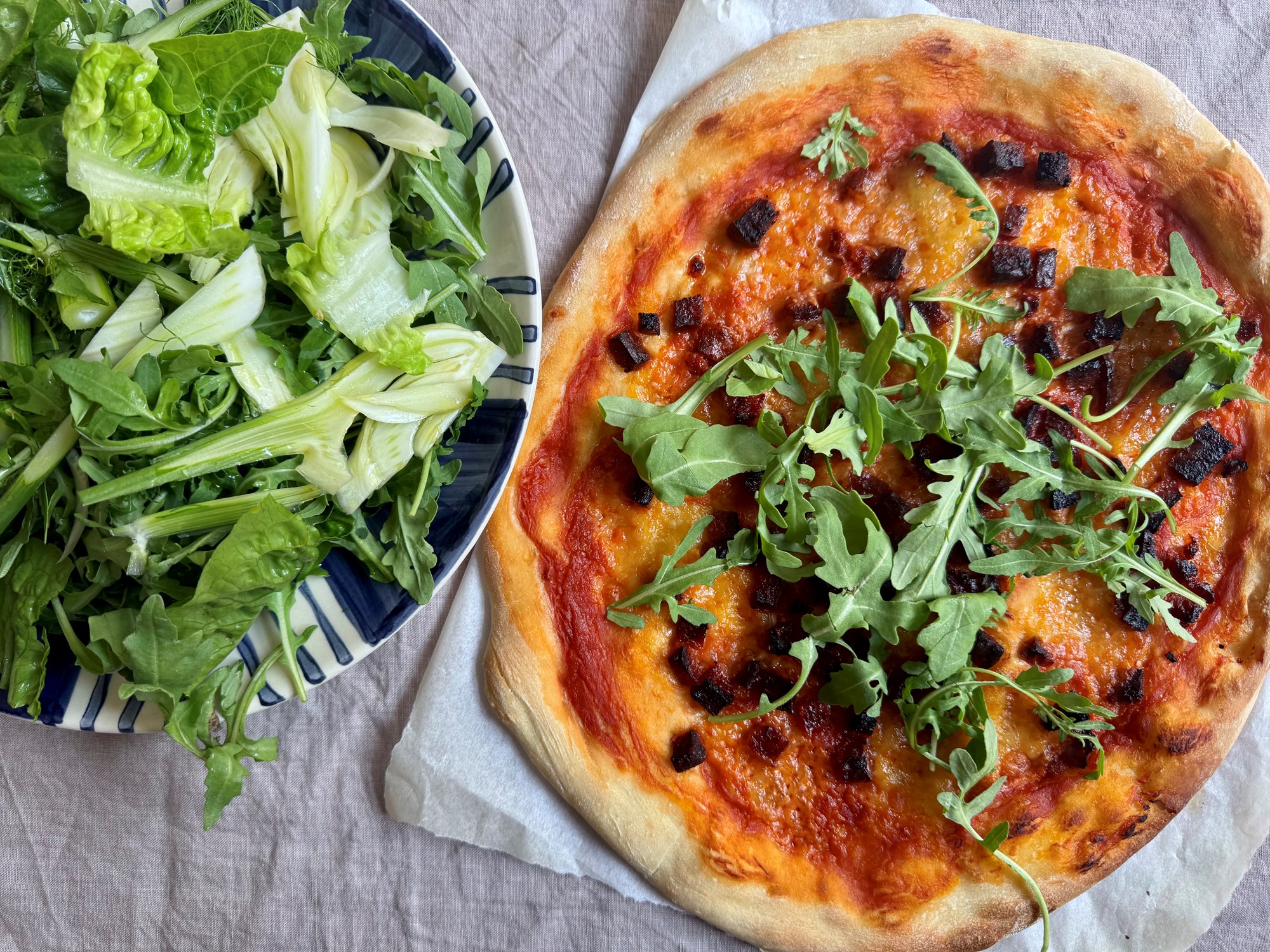 Pizza med spicy salami, frisk mozzarella og sprød salat med fennikel