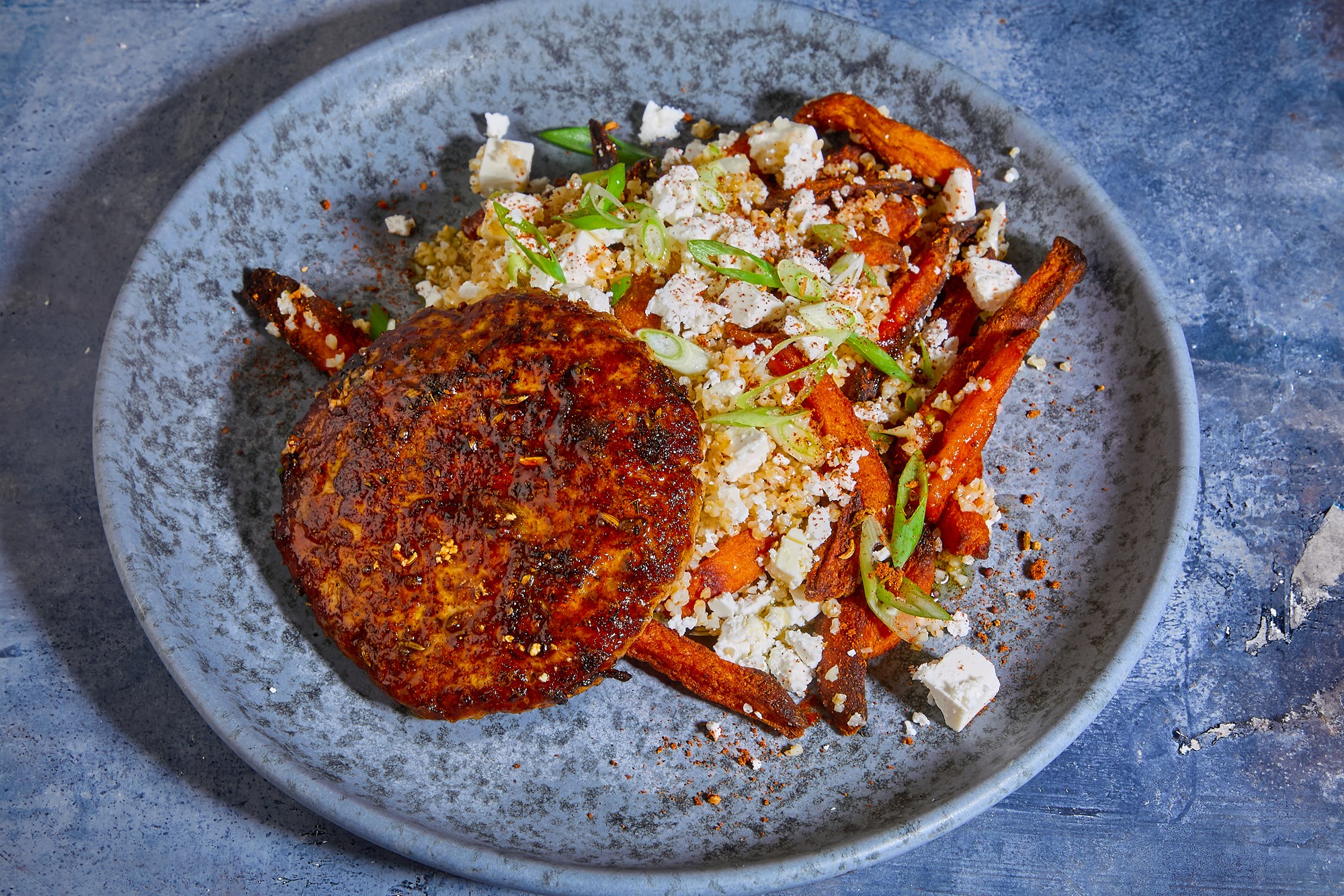 Shawarma-krydrede grisebøffer med bulgur, søde kartofler og oste-drys