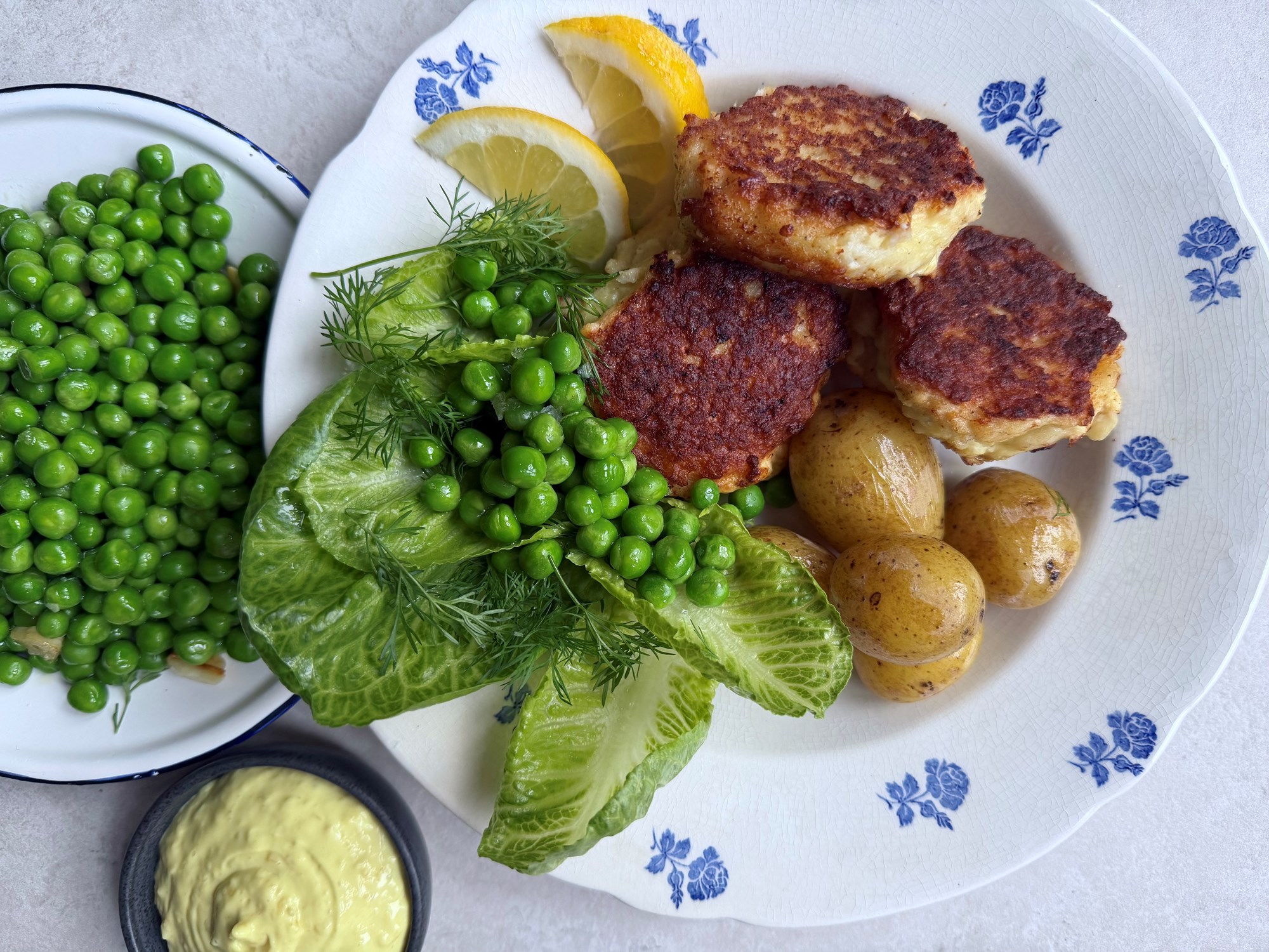 Fiskefrikadeller med kartofler, lune ærter, salat og remoulade