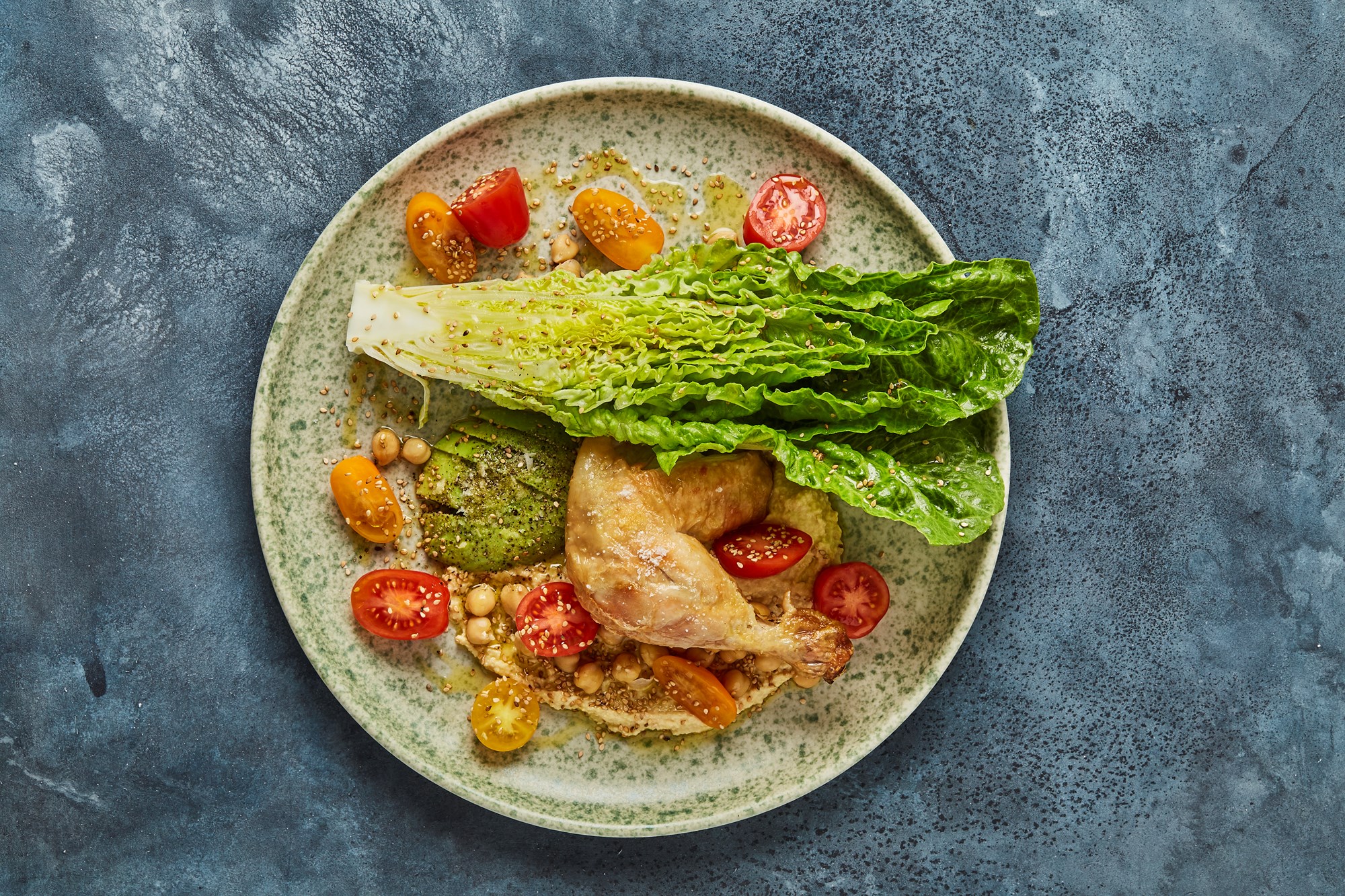 Stegt kyllingelår med hummus og salat af avokado, sesam og tomat