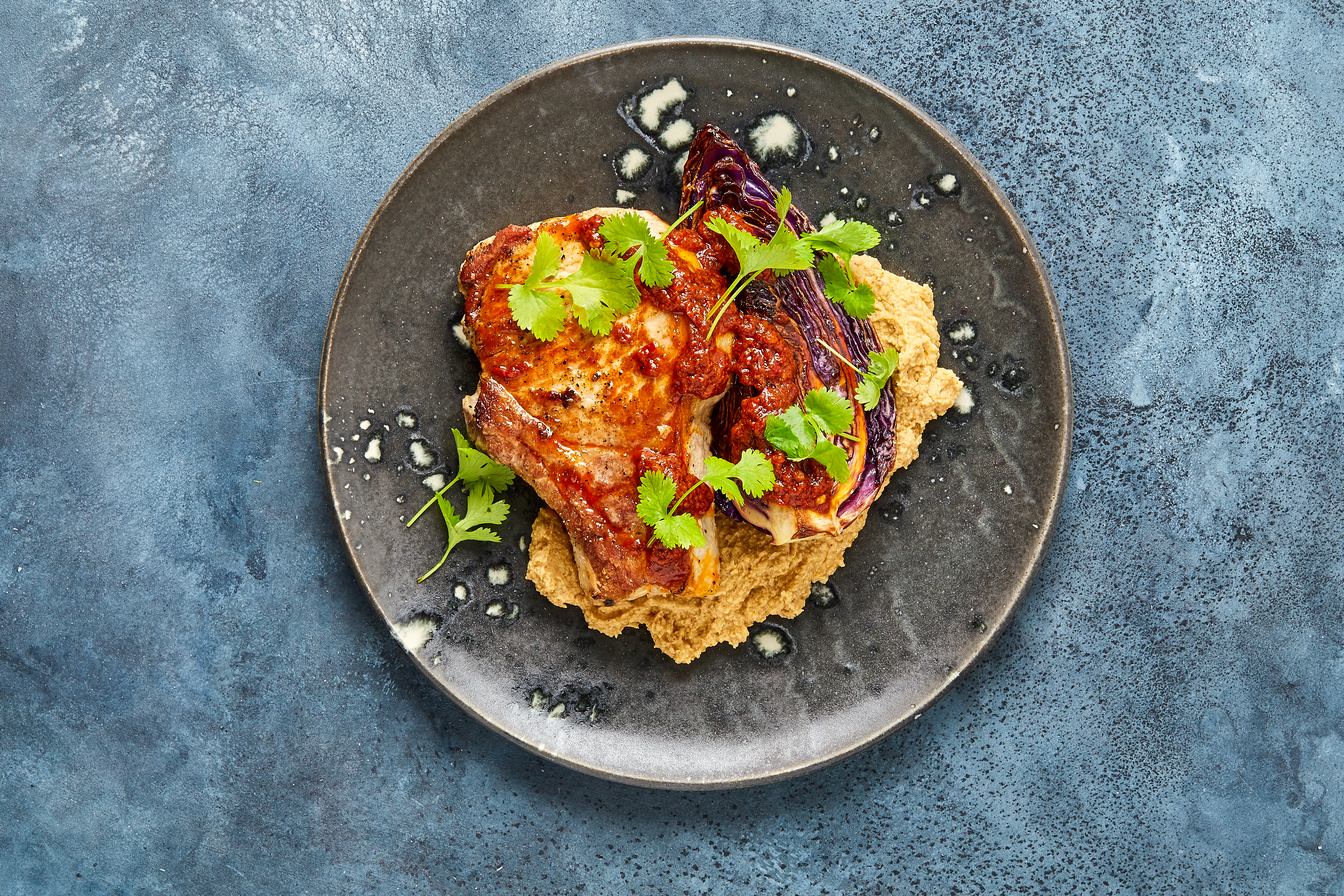 Kotelet af glad gris med hummus, harissa og stegte røde spidskål
