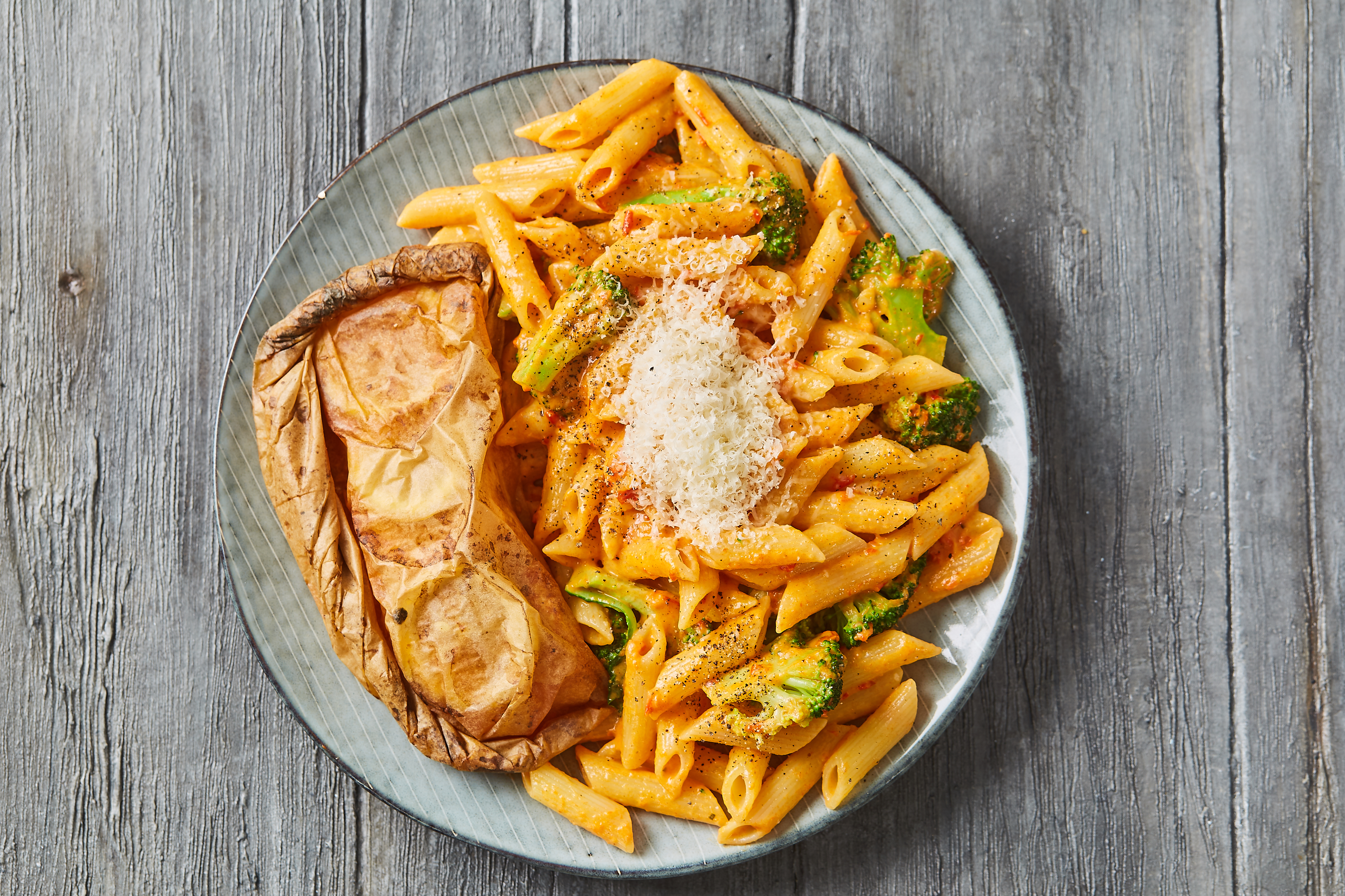 Citronbagt laks en papilotte med broccoli og penne i peberfrugtsauce med parmesan
