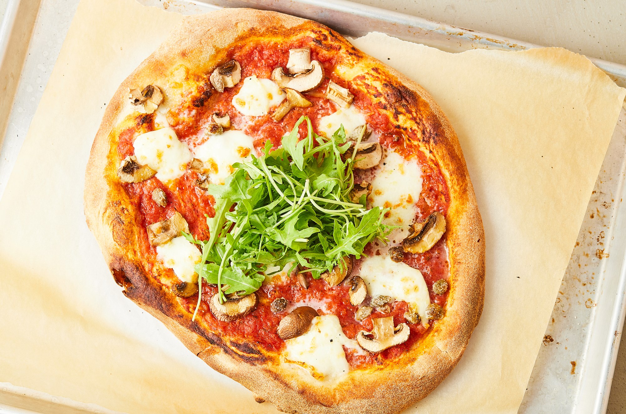 Pizza med tomatsauce, svampe, mozzarella og rucola
