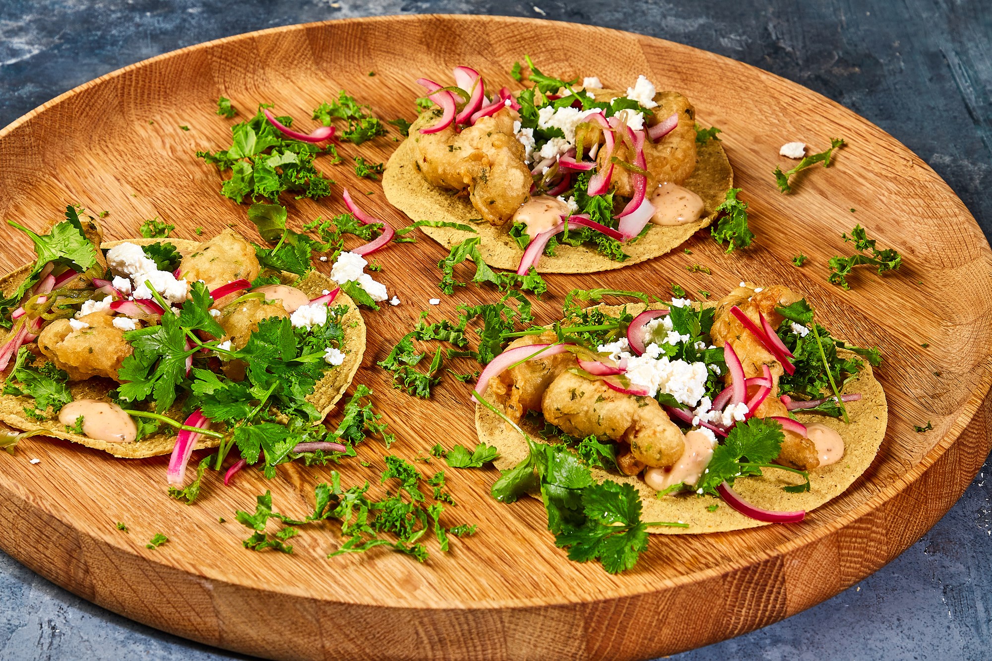 Baja style fish tacos med sprødstegt torsk, grønkål, queso fresco, chilisyltede rødløg, koriander og mexicansk kryddermayo