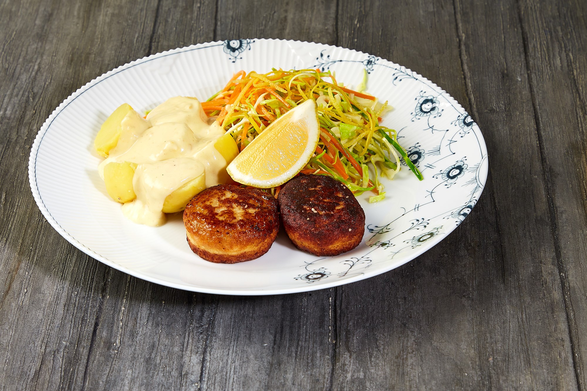 Fiskefrikadeller med remouladesovs og kartofler serveret med spidskål & gulerodssalat