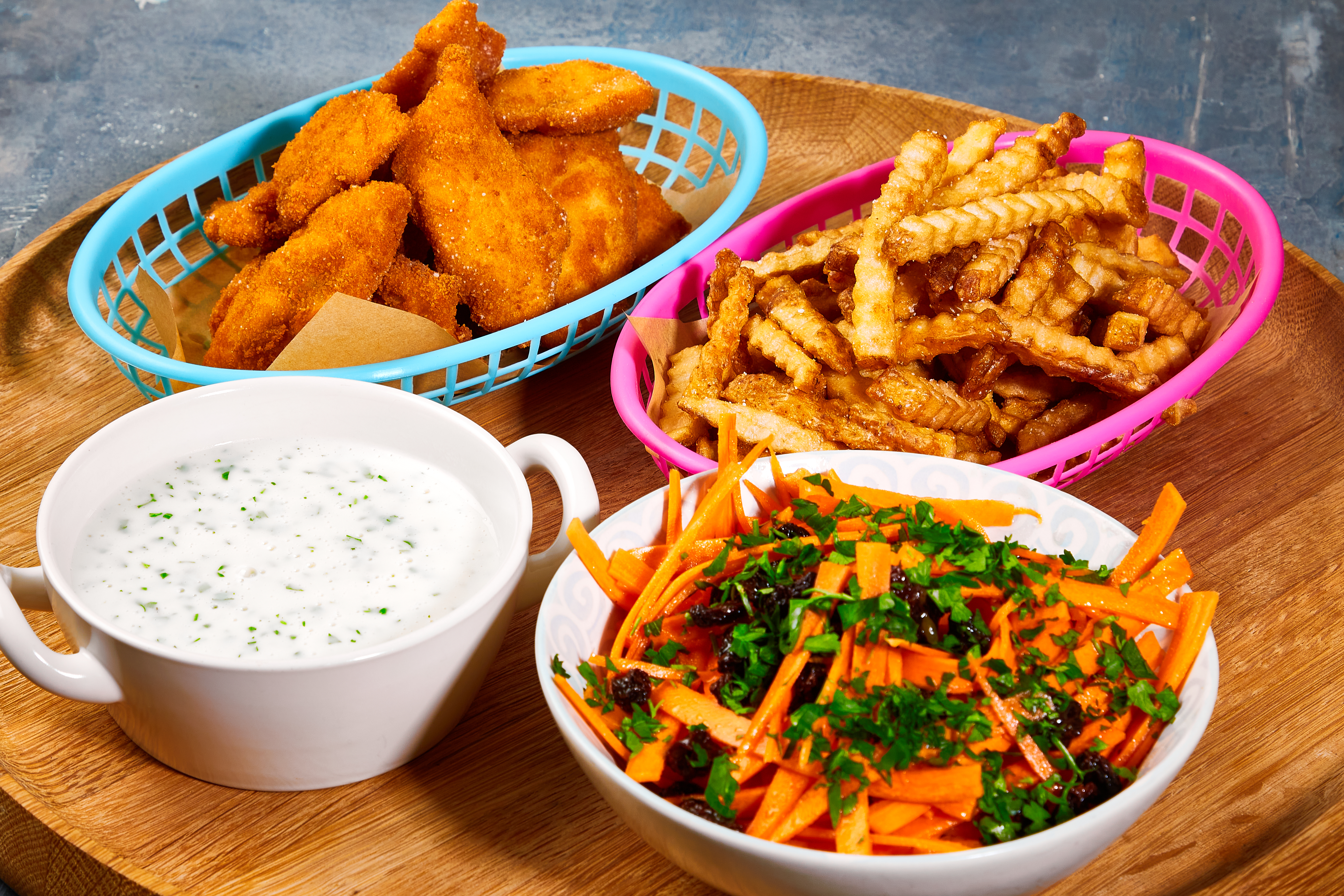 Fiskenuggets med pommes frites, persillesovs og gulerodssalat med appelsin og rosin