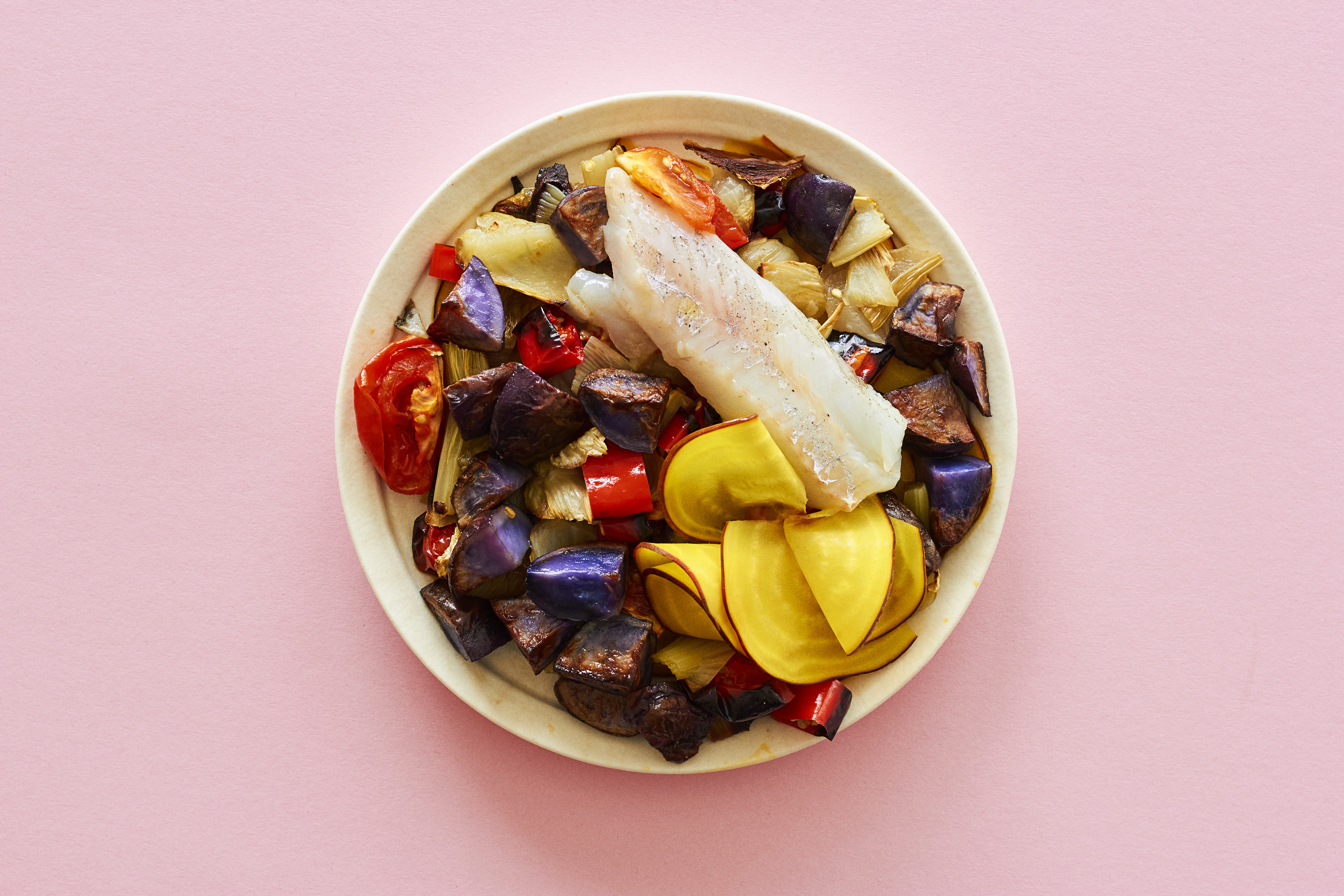 Bowl med bagt torsk i grillede grøntsager med gule beder og blå kartofler