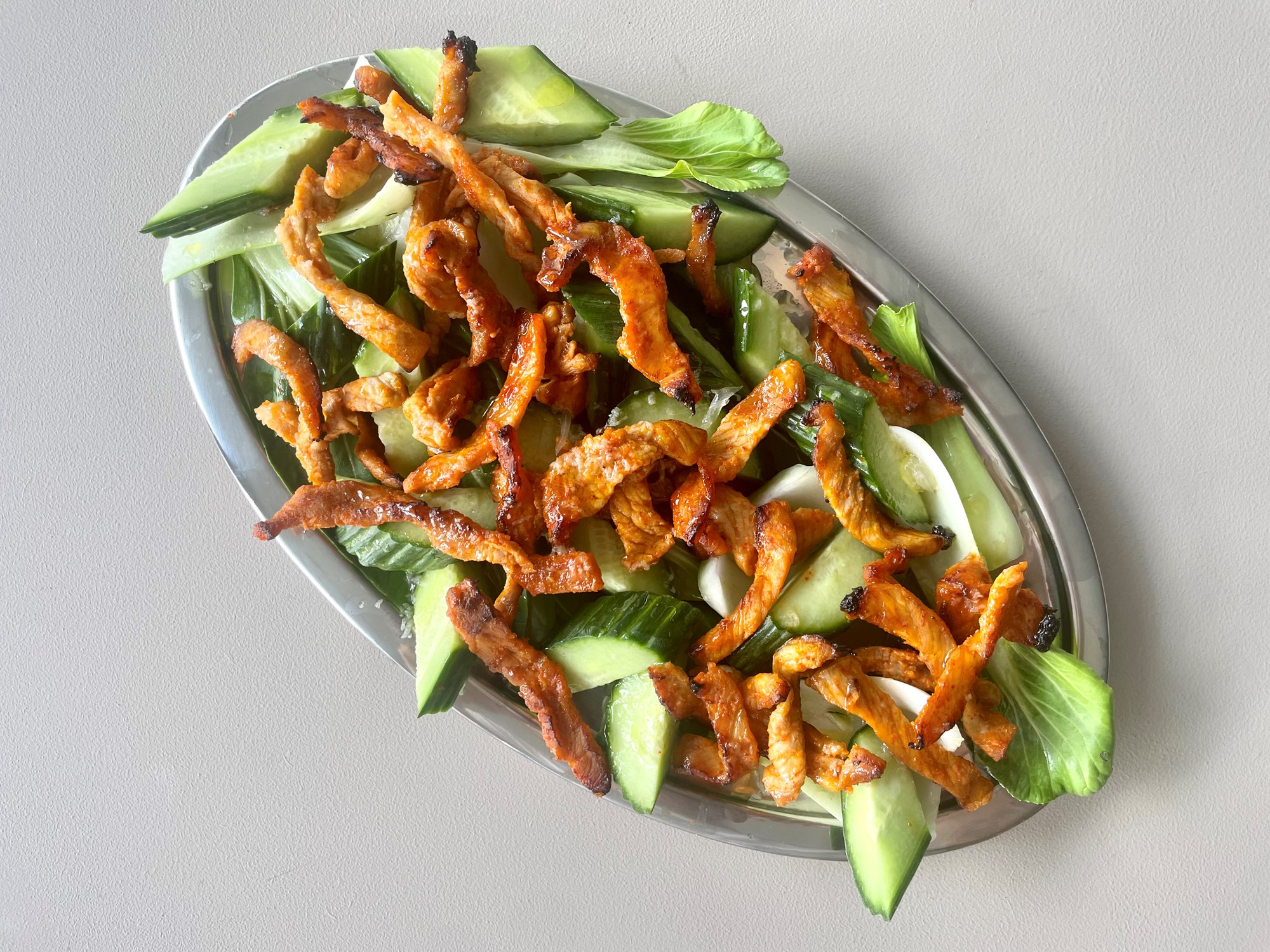 Srirachabagte svinestrimler i frisk nudelsalat med agurk og pak choy