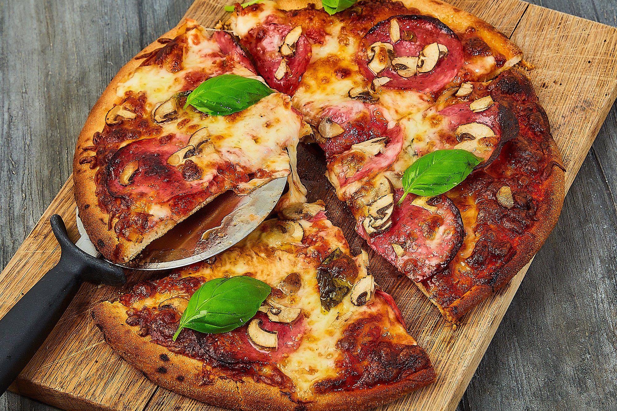 Pizza med tomat, salame Cacciatore og basilikum